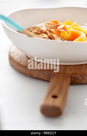 Healthy breakfast. Multigrain flakes with greek yogurt and fruits mango and papaya close up Stock Photo