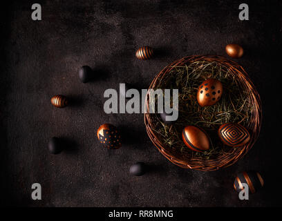Black and gold eggs over black background. Flat lay Stock Photo