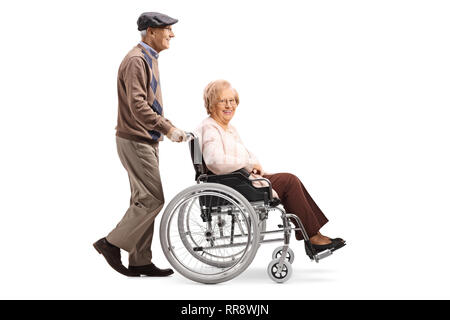 Full length profile shot of a senior man pushing a senior woman in a wheelchair isolated on white background Stock Photo