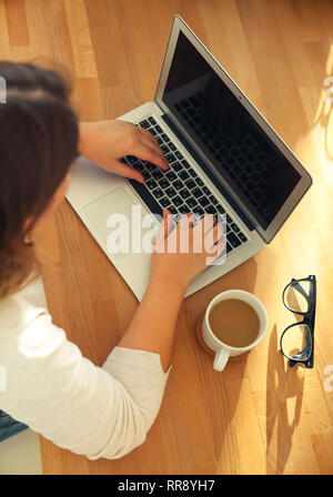 Top view of womans hands typing on laptop keypad with glasses and coffee on the table. Mock up minimal flat lay hero header Stock Photo