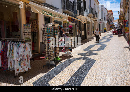 Lagos, Portugal - June 27, 2018: Tourists stop at stores lined along the tiled streets of Lagos on a sunny day. Stock Photo