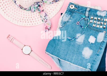 Female girly clothes, blue jeans shorts, hat, watch on pink background Stock Photo