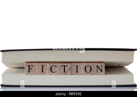 Fiction written on wooden blocks inside a book isolated on a white background with reflection Stock Photo
