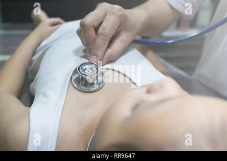 The Doctor examining asian girl and listen heartbeat with stethoscope in the hospital. Stock Photo