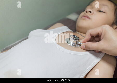 The Doctor examining asian girl and listen heartbeat with stethoscope in the hospital. Stock Photo