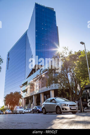 Johannesburg, South Africa, 28 November - 2018: Light reflecting on road as car drives by and hotel building in background. Stock Photo