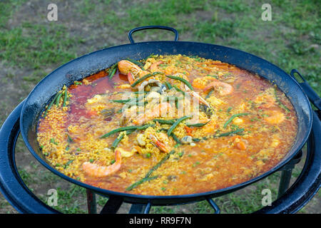 A large pan of seafood paella being prepared outdoors Stock Photo