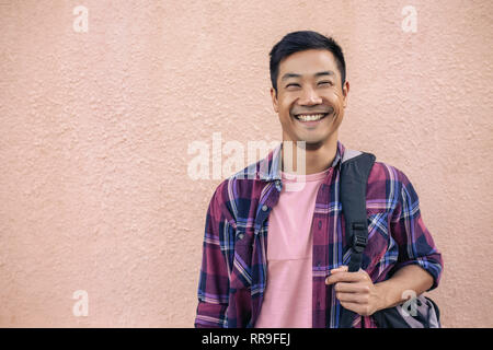 Smiling young man standing outside carrying a backpack Stock Photo