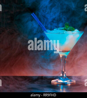 Alcoholic cocktail in a conical glass in a dark dramatic interior with smoke, reflection, violet and red bodily. Concept: luxury party, restaurant, hi Stock Photo