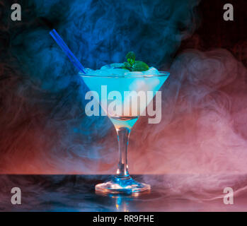 Alcoholic cocktail in a conical glass in a dark dramatic interior with smoke, reflection, violet and red bodily. Concept: luxury party, restaurant, hi Stock Photo