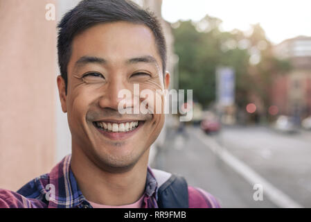Joyful young Asian man standing on a city street Stock Photo
