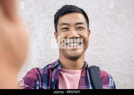 Smiling young Asian man taking a selfie in the city Stock Photo