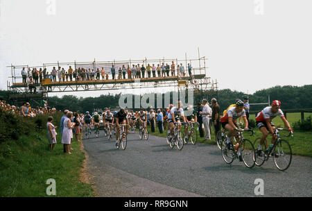 1960s, spectators standing on a gantry watching cyclists competing in The Tour of Britain cycle race going underneath it, England, UK. Stock Photo