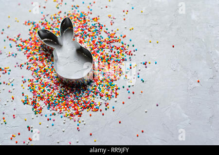 Easter Concept, Sugar Sprinkles and Bunny Cookie Cutter on Grey Background, Sweet Easter Treat, Copy Space Stock Photo