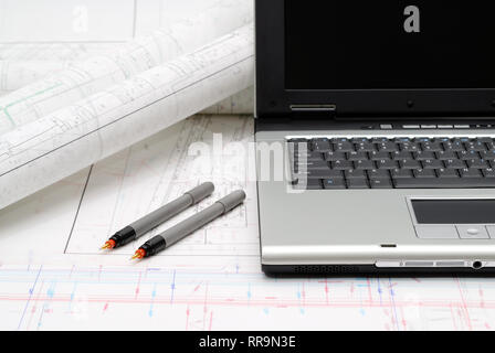 Computer with architectural plans lying on table Stock Photo