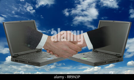 Businessmen handshake. Two male hands emerging from laptops. Blue sky and white clouds in background Stock Photo