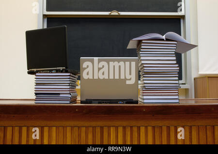 Laptop and books lying on table in lecture hall Stock Photo
