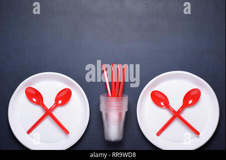 Disposable tableware plates and spoons. Plastic contaminates the earth and water. Concept of  environmental pollution. Top view. Stock Photo