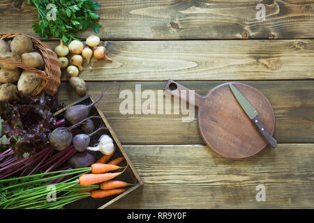 Fresh vegetables from carrot, beetroot, onion, garlic, potato on old wooden board. Top view. Autumn still life. Gardening. Copy space on cutting board Stock Photo