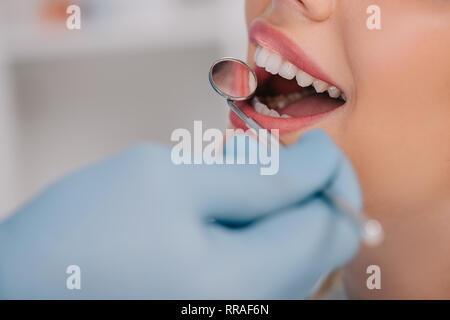 cropped view of dentist examining teeth of young woman with mouth mirror Stock Photo