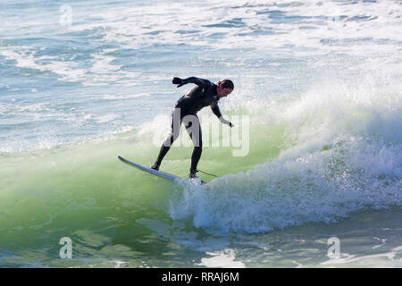 Bournemouth, Dorset, UK. 25th Feb, 2019. UK weather: big waves and plenty of surf create ideal surfing conditions for surfers at Bournemouth beach on a lovely warm sunny day expected to be the hottest day of the year and hottest February day ever.  Surfer on surf board riding the waves. Credit: Carolyn Jenkins/Alamy Live News Stock Photo
