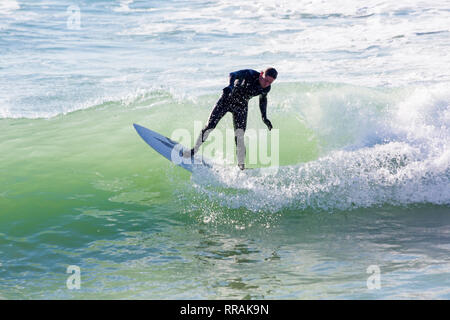 Bournemouth, Dorset, UK. 25th Feb, 2019. UK weather: big waves and plenty of surf create ideal surfing conditions for surfers at Bournemouth beach on a lovely warm sunny day expected to be the hottest day of the year and hottest February day ever. Surfer on surf board riding the waves. Credit: Carolyn Jenkins/Alamy Live News Stock Photo