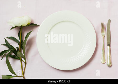 Spring romantic dinner. Elegance table setting peony flowers on tablecloth. Top view. Stock Photo