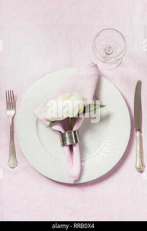 Spring romantic dinner. Elegance table setting peony flowers on tablecloth. Top view. Stock Photo