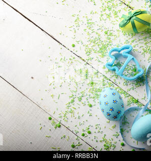 Cookie cutter in shape of easter bunny with painted eggs on white table Stock Photo