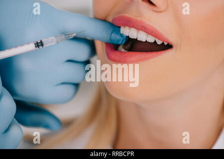 cropped view of dentist giving local anesthesia injection to woman Stock Photo