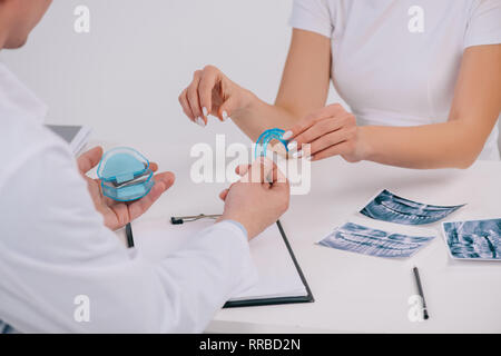 cropped view of woman taking trainer dental braces from orthodontist during appointment isolated on white Stock Photo