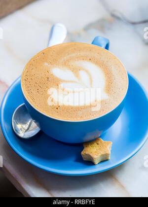 Cappuccino with latte art in a blue cup. Stock Photo