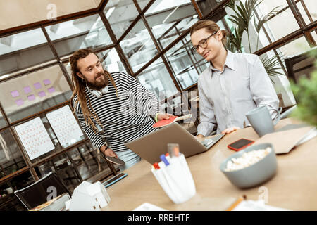 Pleasant nice man giving a table tennis rocket to his colleague Stock Photo