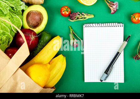 Shopping list, recipe book, diet plan. Grocering concept. Full paper bag of different fruits and vegetables, ingredients for healthy cooking. healthy  Stock Photo