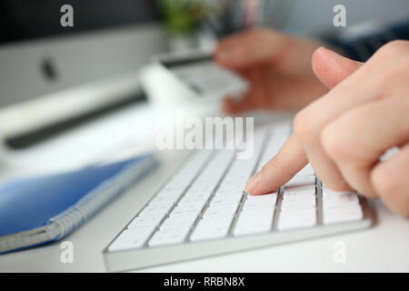 Female arms hold credit card press buttons Stock Photo