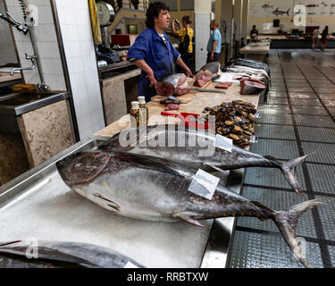 Fishmonger selling tuna at the Lavradores fish market, Funchal, Madeira, Portugal. Stock Photo