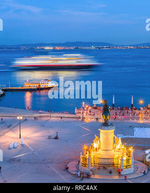 Aerial view from Triumphal Arch at evening Lisbon city embankment, cruise liner in motion blur, people walking at Commerce Square in dusk, King Jose I Stock Photo