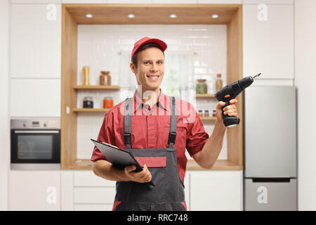 Repairman holding a clipboard and a drill machine in a kitchen Stock Photo