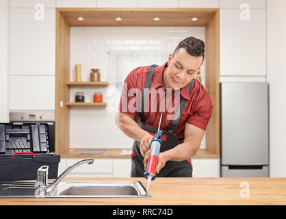 Plumber using a silicone tube on a sink inside a modern kitchen Stock Photo