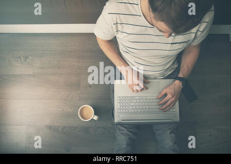 work from home - man sitting on the floor and using laptop computer. top view Stock Photo