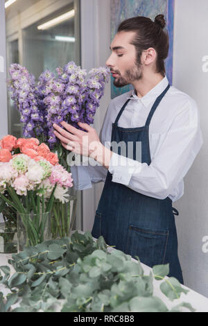 Small business. Male florist in flower shop. Floral design studio, making decorations and arrangements. Flowers delivery, creating order. The man in female profession. Gender equality concept Stock Photo