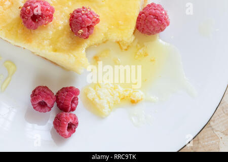 Close-up cheese casserole with raspberries drizzled with honey on white plate.  Stock Photo