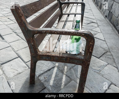 Empty glass beer bottle on park bench Stock Photo