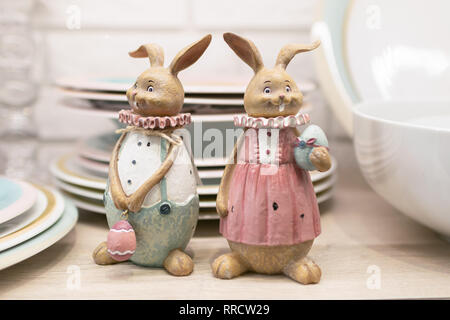 Two Easter pottery hare on a kitchen table shelf. Ceramic figurines for serving the festive table. Selective focus Stock Photo