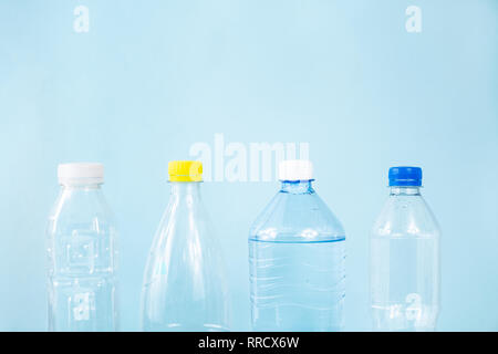 Plastic waste concept: discarded various water bottles in blue background, detailed view. Single use plastic bottles standing in row, image depicting  Stock Photo