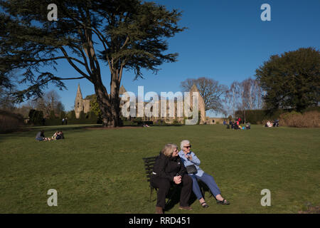 Two women, mother and daughter, sitting on bench in public gardens in West Sussex England Stock Photo