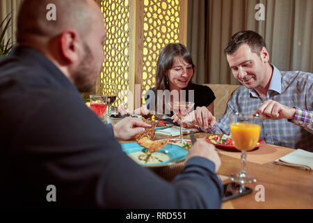 The third is superfluous. couple in love is having dinner in a restaurant with a lonely friend Stock Photo
