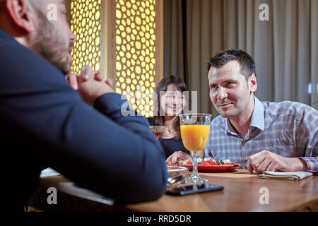 The third is superfluous. couple in love is having dinner in a restaurant with a lonely friend Stock Photo