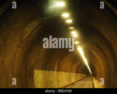 Perspective view of empty round concrete tunnel illuminated with lamps on ceiling Stock Photo