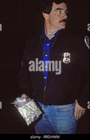 Langley Park, Maryland. USA, November 19, 1988 Prince Georges County Police conduct street level crack cocaine busts. Police officer holds a  evidence bag full of crack cocaine rocks and cash that was seized from a street dealer Credit: Mark Reinstein / MediaPunch Stock Photo